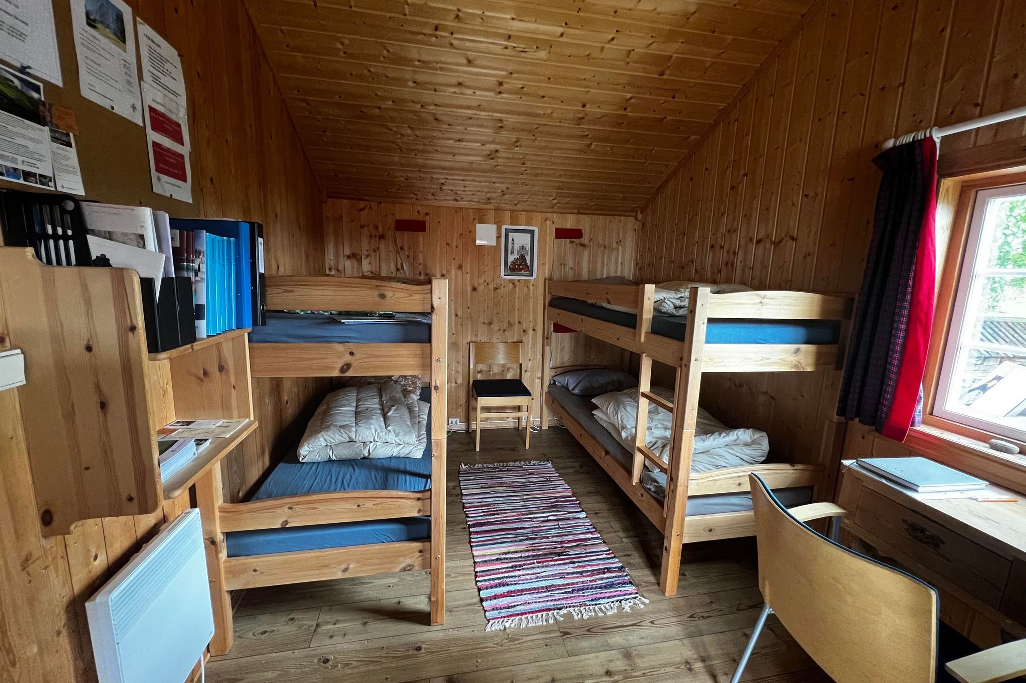 Sovesal i Pilegrimsstua Ringsaker med to køyesenger i et rom med trevegger, tregulv og vindu.
